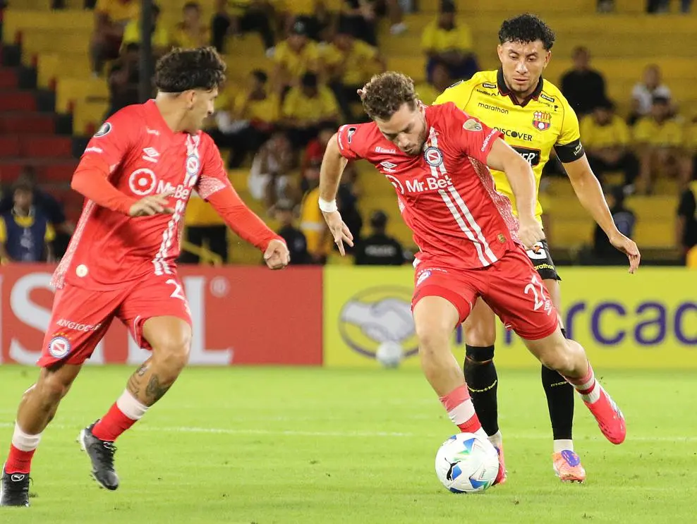 Joao Rojas en cancha tratando de recuperar el balón ante jugadores de Argentinos Juniors.